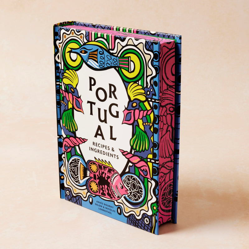 Paperback cookbook featuring authentic Portuguese recipes and ingredients, with colorful dishes and traditional cooking tools.