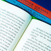 Four paperback books from Suzanne Collins' Hunger Games series by Scholastic, featuring cover art from the box set collection.