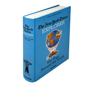 Hardcover book titled "The New York Times: Explorer 100 Trips Around The World" by Taschen, featuring colorful travel images on the cover.