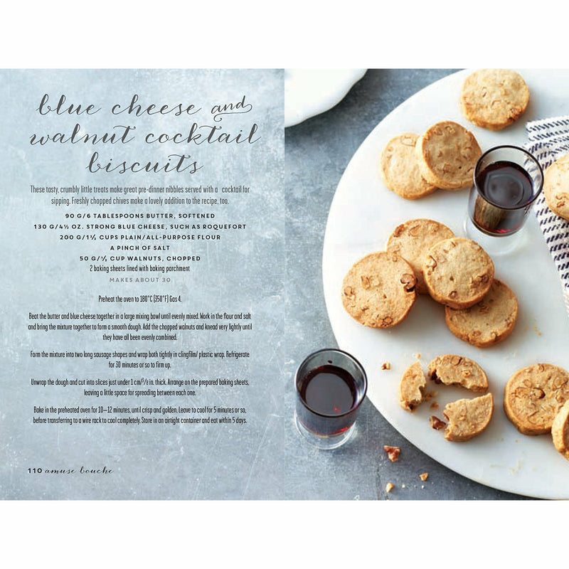 Open hardcover book titled "Parisian Cocktails" by Laura Gladwin, featuring elegant drinks and bites from Paris on white background.
